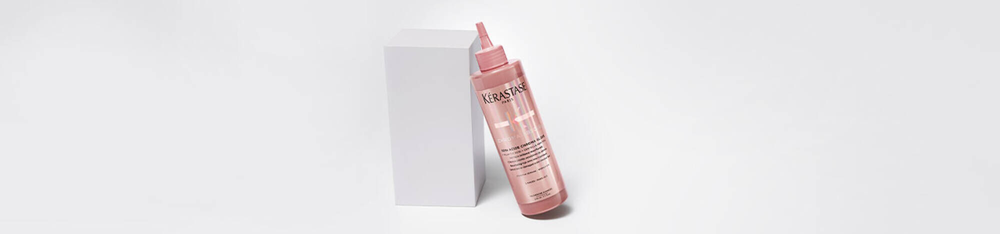 Bottle of Chroma Absolu Chroma Gloss Treatment leaning on a white block