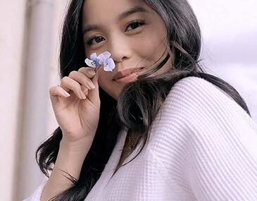 Model with dark hair holding a white flower