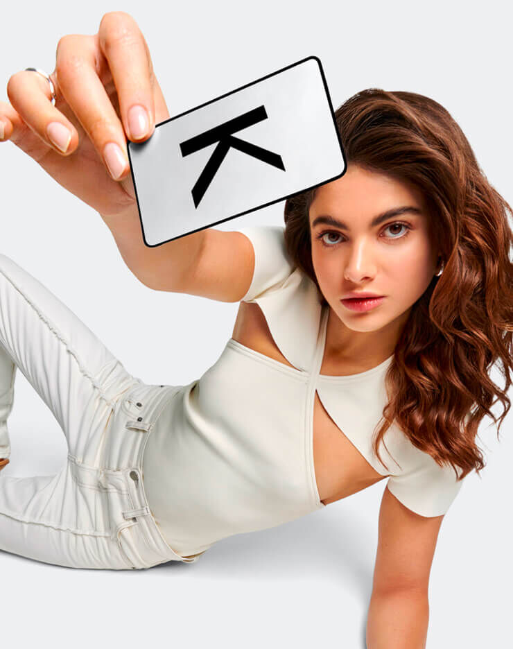 Model sitting on the ground holding a Kerastase Loyalty Card in her hand