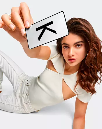 Model sitting on the ground holding a Kerastase Loyalty Card in her hand