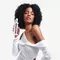 Model with dark curly hair holding a bottle of Premiere Decalcifying Repairing Treatment