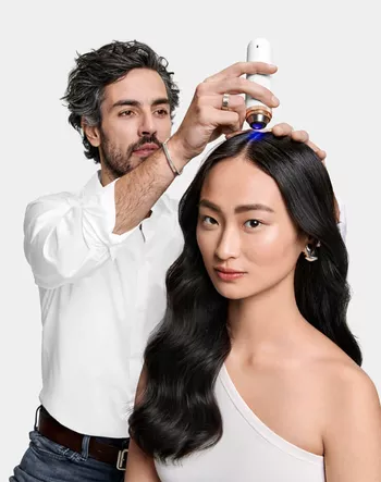 Hair expert using a diagnostic tool to examine the scalp of a model with long black hair