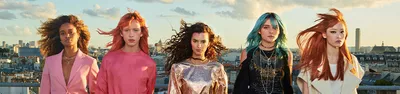 Group of models with vibrant hair colors on rooftop at sunset