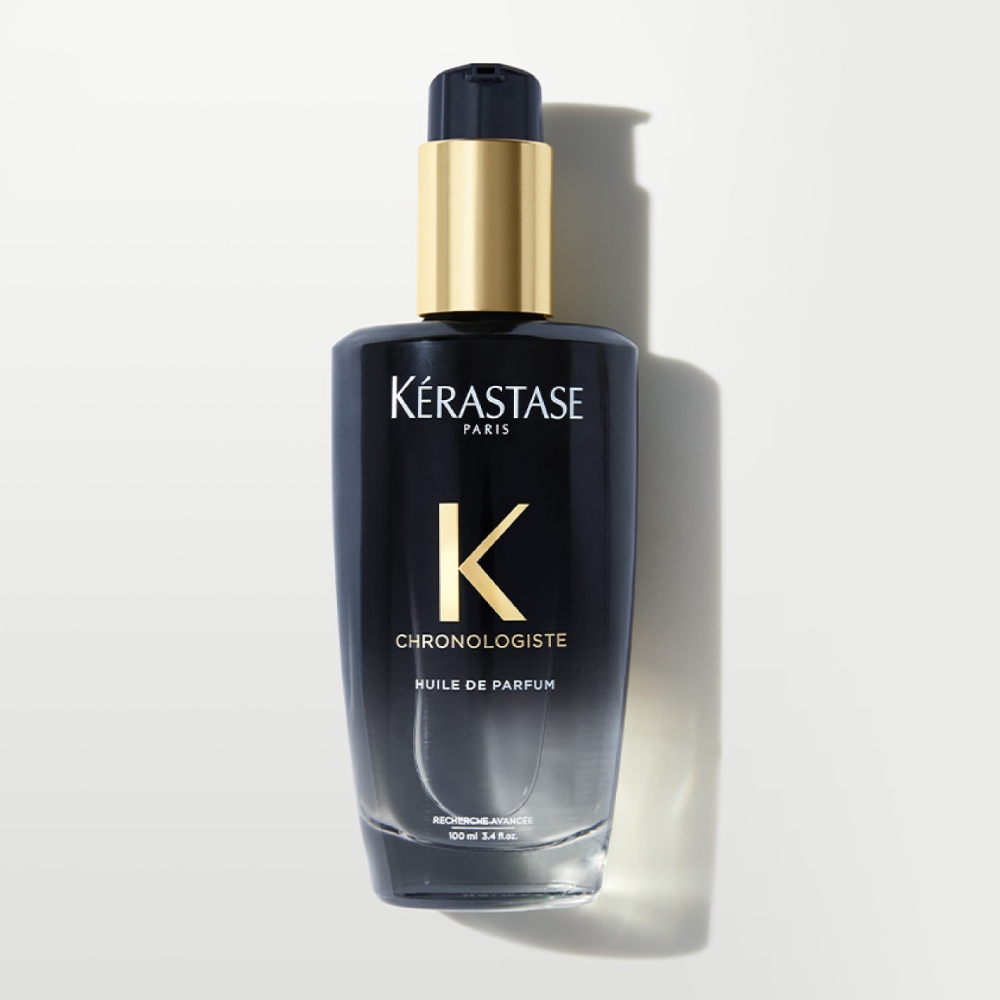 Chronologiste Huile De Parfum présentée sur un fond gris épuré. L’huile offre un mélange raffiné de parfums envoûtants tout en apportant brillance et nutrition aux cheveux.