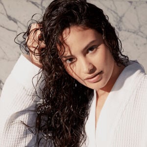 A woman touches her damp, wavy hair