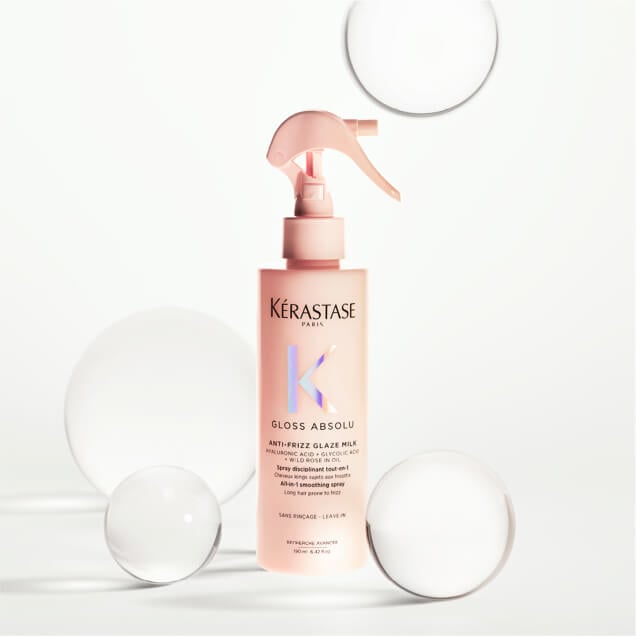 Kérastase Gloss Absolu Anti-Frizz Glaze Milk bottle surrounded by glass decor